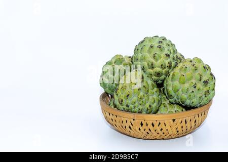 Pommes Custard vertes fraîches gardées sur un panier en bois avec arrière-plan blanc Banque D'Images