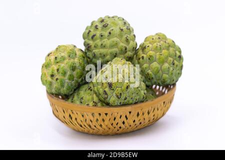 Pommes Custard vertes fraîches gardées sur un panier en bois avec arrière-plan blanc Banque D'Images