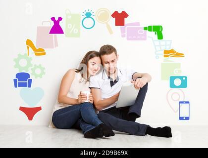 Achats en ligne. Couple millénaire avec ordinateur tablette entouré de différentes icônes de biens ménagers, collage Banque D'Images