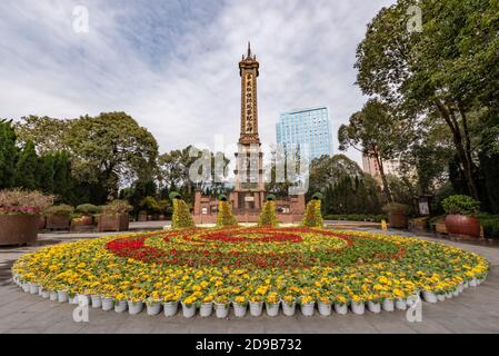 Parc du peuple, Chengdu, province du Sichuan, Chine - 16 février 2020 : Tour de monument dans le parc du peuple avec - à la mémoire de la bataille de XinHaiBaolu - écrit en chinois avec lit de fleurs en premier plan Banque D'Images