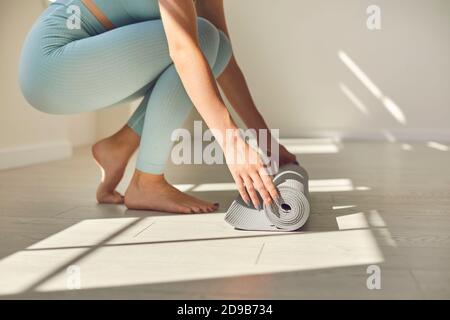 Faites monter la jeune femme pieds nus dans un tapis de yoga sport avant de pratiquer le yoga dans la salle de gym Banque D'Images