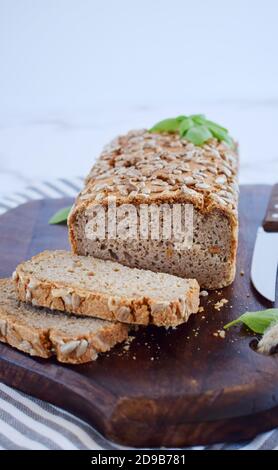 Le pain de sarrasin sans gluten à croûte dorée, parsemé de graines de tournesol, repose sur une table en bois. Une recette maison saine. Grains de vert Banque D'Images