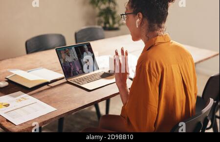 Femme d'affaires à la maison ayant un appel de vidéoconférence avec des collègues. Femme saluant un collègue lors d'une conférence Web. Banque D'Images