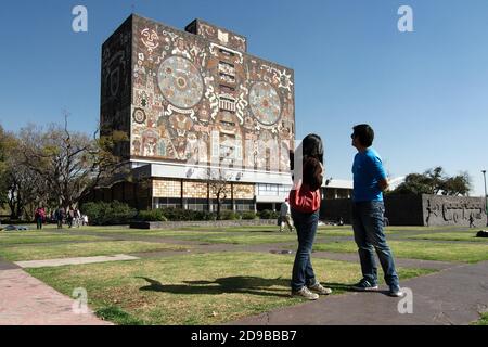 Mexico, Mexique - 2020 : les étudiants regardent le bâtiment de la bibliothèque centrale du campus de l'Université nationale autonome du Mexique, un site classé au patrimoine de l'UNESCO. Banque D'Images