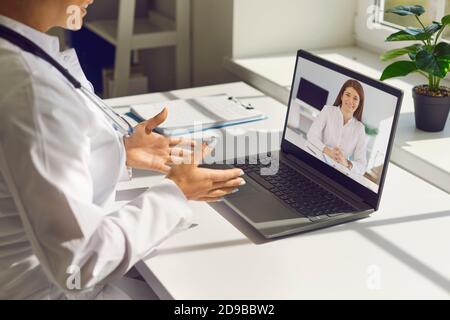 Deux jeunes collègues de médecins communiquent à l'amiable par le biais d'un appel vidéo sur un ordinateur portable. Banque D'Images