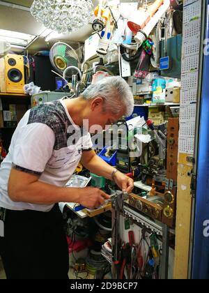 d20/3/2019 vieil homme copie une clé avec machine à copier dans un petit magasin bondé, (thème de serrurier. Touches vierges pour la coupe. Ouvre-porte) Banque D'Images