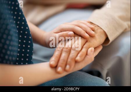 Petite-fille soutenant sa grand-mère. Les mains en gros plan. Banque D'Images