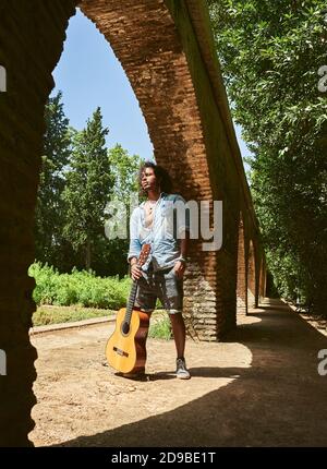 Jeune homme à la peau brune avec une guitare espagnole classique. Banque D'Images