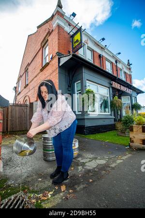 Laura Martindale, directrice de la maison publique Rocket de Whiston, déverse la bière gâtée qui s'est éteinte après que le pub a été placé dans la troisième catégorie et fait maintenant l'objet d'un confinement de quatre semaines avant un confinement national pour l'Angleterre à partir de jeudi. Banque D'Images