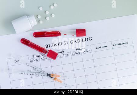 Journal de glycémie avec tubes d'échantillons de sang, seringues et pilules vue du dessus. Journée mondiale du diabète, 14 novembre concept Banque D'Images