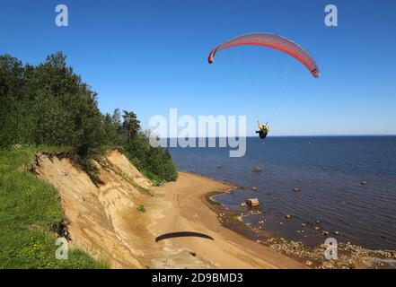 Parapente homme dans les airs. Ciel bleu et mer en arrière-plan Banque D'Images