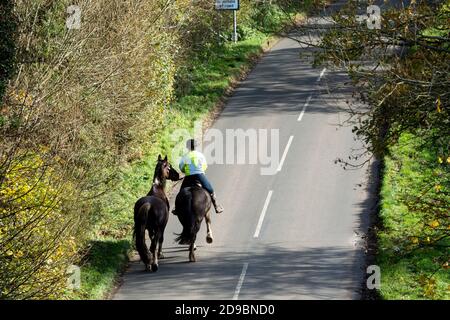 Cavalier menant un autre cheval sur une route de campagne, Warwickshire, Royaume-Uni Banque D'Images