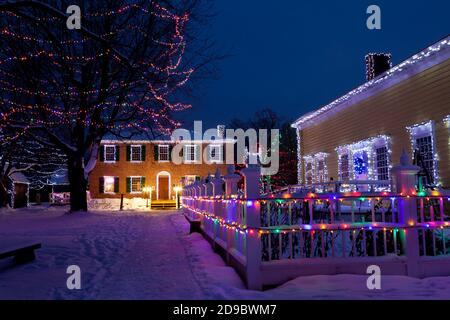 Édifices du patrimoine, arbres et clôtures décorés de lumières de Noël au Upper Canada Village, Morrisburg, Ontario, Canada Banque D'Images