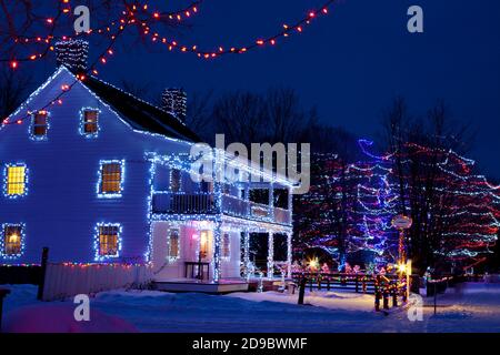 Édifices du patrimoine, arbres et clôtures décorés de lumières de Noël au Upper Canada Village, Morrisburg, Ontario, Canada Banque D'Images