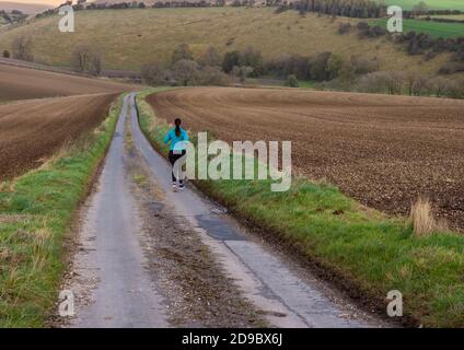 Burdale, North Yorkshire, Angleterre, 28/10/2020 - route de campagne menant à la distance avec une femme solitaire Jogger Banque D'Images