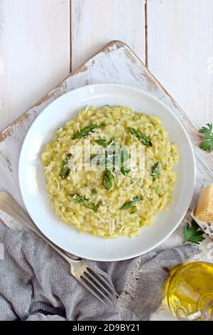 Risotto italien aux asperges printanières et au parmesan sur fond clair. Vue de dessus avec espace de copie. Banque D'Images