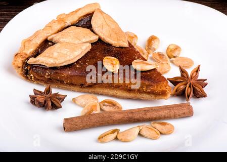 Une tarte à la citrouille décorée de biscuits en forme de feuilles. Assiette blanche avec un morceau de tarte, cannelle, anis étoilé et graines de citrouille. Banque D'Images
