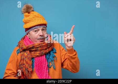 Homme âgé avec moustache portant plusieurs foulards et chapeaux pointant sur le côté Banque D'Images