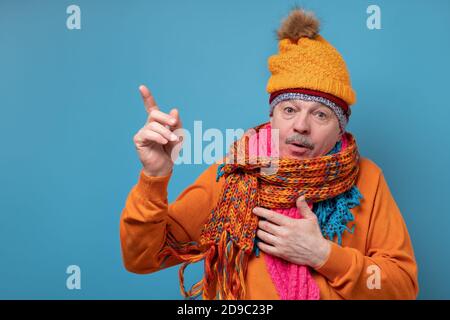 Homme âgé avec moustache portant plusieurs foulards et chapeaux pointant sur le côté Banque D'Images