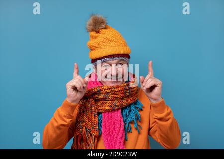 Homme âgé avec moustache portant plusieurs foulards et chapeaux pointant sur le côté Banque D'Images
