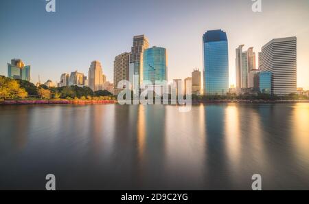 Lac dans le parc public sous les gratte-ciel à Sunrise. Benjakiti Park à Bangkok, Thaïlande Banque D'Images