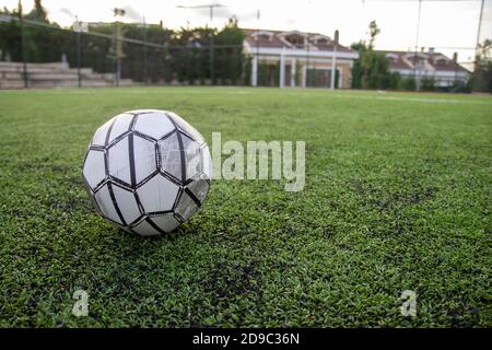 Ballon de football sur gazon artificiel brillant et vert foncé à stade public de football extérieur ou de futsal Banque D'Images