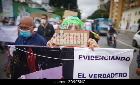 Caracas, Venezuela. 04e novembre 2020. « USD 5 - Penion mensuel - #State violence », est écrit sur la petite affiche d'une femme portant un masque facial et une capuche lors d'une manifestation au milieu de la pandémie de Corona. Appelé selon les chiffres officiels, 93,100 personnes au Venezuela ont contracté Covid-19 et 810 personnes en sont mortes. Les médias fidèles du gouvernement assurent que 94 pour cent des patients atteints du virus corona se rétablissent. Selon ces chiffres, le taux de mortalité est inférieur à celui de la Suisse. Credit: Rafael Hernandez/dpa/Alay Live News Banque D'Images