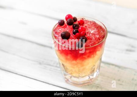 Cocktail d'alcool rouge avec vodka et canneberges et raisins de Corinthe noirs sur la vitre Banque D'Images