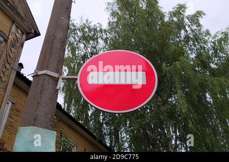 La signalisation routière est suspendue sur un lampadaire en béton dans la ville, sur fond de bois et de ciel. Transport routier. Concept de sécurité routière. Rue. Arrière-plan de voyage. Banque D'Images