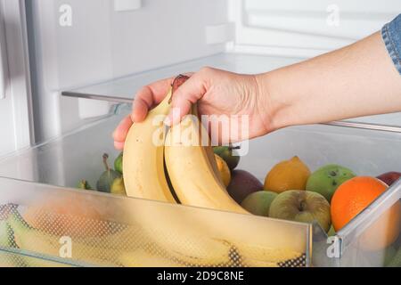 Femme obtenant des bananes fraîches d'un réfrigérateur. Gros plan. Banque D'Images