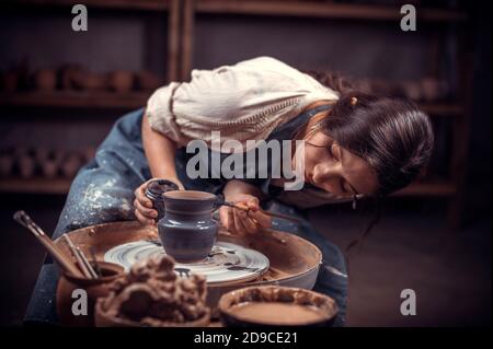 Le sculpteur Potter professionnel élégant travaille avec de l'argile sur une roue de Potter et à la table avec les outils. Production artisanale. Banque D'Images