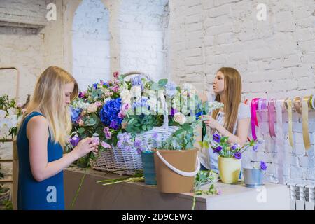 Deux artistes fleuristes professionnels, fleuristes en train de réaliser un grand panier floral avec des fleurs à l'atelier, fleuriste. Fleuriste, fait main, mariage Banque D'Images