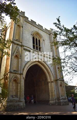 La porte de l'abbaye, un portier en pierre du XIVe siècle et une entrée aux jardins de l'abbaye à Bury St Edmunds, Suffolk, Angleterre. Les gens passent par l'arcade. Banque D'Images