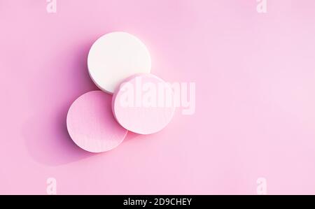 Éponges cosmétiques aux couleurs pastel sur fond rose tendre. Banque D'Images