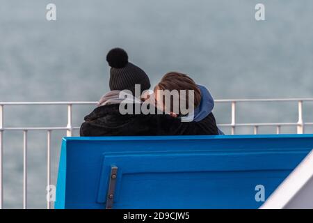 un jeune couple embrassant et tenant ou embrassant sur un banc au bord de la mer. les jeunes amoureux embrassant à l'extérieur. Banque D'Images