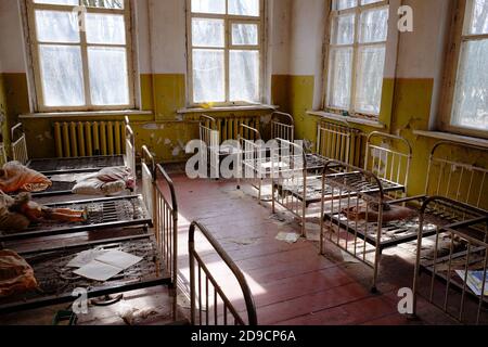 Lits d'enfants dans une école maternelle abandonnée. L'intérieur d'une pièce dans l'un des bâtiments de la zone d'exclusion radioactive de Tchernobyl. Banque D'Images