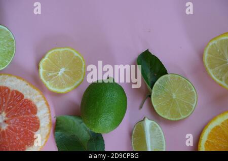 Mise à plat des agrumes comme lime et citron citron avec les feuilles des arbres sur le rose clair, rendant une trame Banque D'Images