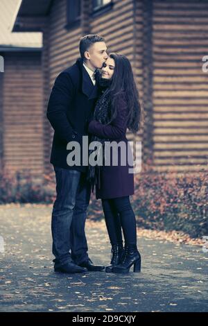 Joyeux jeune couple de mode embrassant sur la rue homme élégant et femme en manteaux classiques Banque D'Images