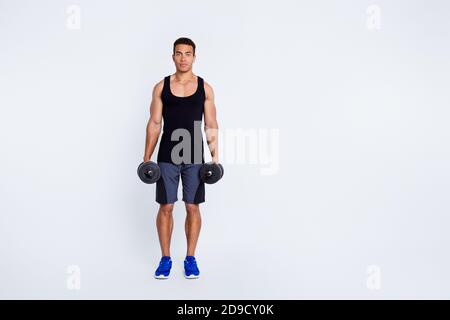 Vue sur toute la longueur du corps de son beau attrayant content sportive gars faisant l'exercice tenant dans les mains dumbbell exercice-out progression isolée Banque D'Images