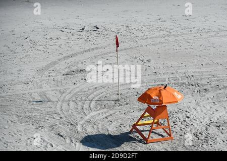 Un sauveteur orange se tient sur la plage avec un bâton de drapeau près Banque D'Images