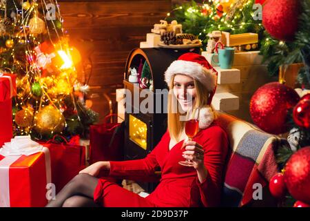 Santé. La veille de noël pour fille offre une atmosphère chaleureuse. Des moments agréables. Joie de Noël. Femme décorée intérieur guirlande lumières boire du champagne. Noël Banque D'Images