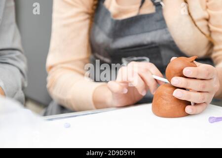 Gros plan des mains de femme travaillant avec fondant pour décorer un gâteau - femme peinture argile avec pinceau et teintures - femme artisan Banque D'Images