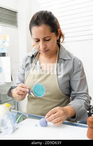 Femme hispanique travaillant dans sa pâtisserie - Latina femme travailler avec fondant pour décorer un gâteau - pâtisserie entrepreneur chef - femme faisant l'artisanat avec Banque D'Images