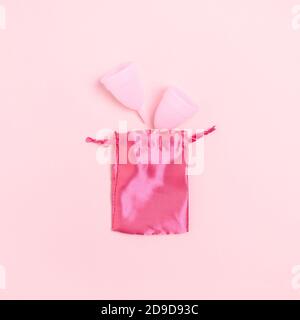 Vue de dessus des tasses menstruelles avec un sac sur rose arrière-plan Banque D'Images
