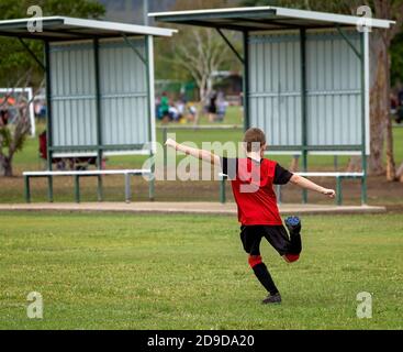 Un jeune joueur de football pratique ses coups de pied sur le terrain avant une partie Banque D'Images