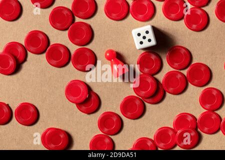 Concept de jeux de société, pièces rouges, tiré du dessus avec une matrice sur fond marron Banque D'Images