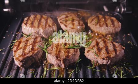 Délicieux bifteck de viande juteuse sur le gril. Faire cuire au bœuf à la sauce au roaster électrique, au romarin, au poivre noir et au sel. Ralenti. Banque D'Images