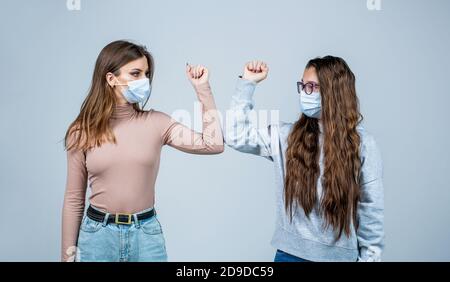 Bosse du coude. Les amis en masque médical protecteur sur son visage saluent leurs coudes dans une quarantaine. Masque médical des amis. Les gens portent un masque. Amis Banque D'Images