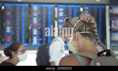 Femme caucasienne à l'aéroport de Suvarnabhumi avec masque médical protecteur. Carte d'information de vol. Coronavirus sars-cov-2 covid-19. Banque D'Images