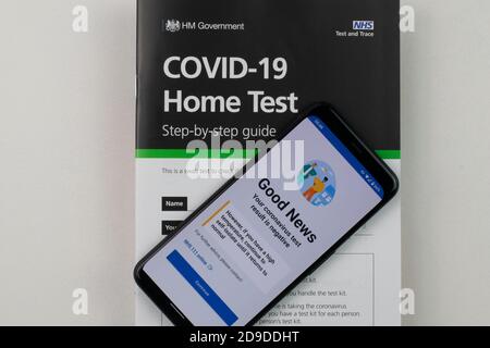 Résultat du test du coronavirus négatif sur le téléphone mobile reposant sur la brochure d'instructions pour la trousse de test à domicile COVID-19. Banque D'Images